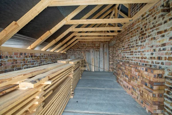尚未完工的有混凝土地面的砖房的内部 可用于贴石灰的光秃秃的墙壁和正在建造的木制屋顶框架阁楼 — 图库照片