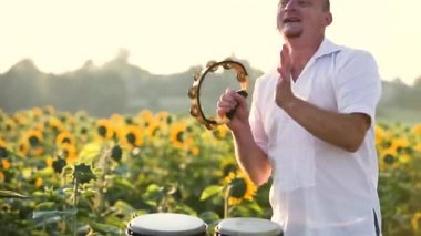 Yeşil yaz tarlasında tef çalıp enerjik bir şekilde dans eden mutlu dansçı..