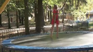 Yaz parkında trambolinde zıplayan kız çocuğu..