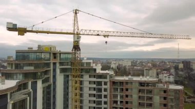 Daire ya da ofis yüksek binası yapım aşamasında. Tuğla duvarlar, cam pencereler, iskeleler ve beton destek sütunları. Parlak mavi gökyüzü arkaplanındaki kule vinci kopyala.