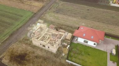 Biri ahşap çatı iskeleti ve diğeri de kırmızı kiremit çatılı iki özel evin yukarıdan aşağıya bakan görüntüsü..