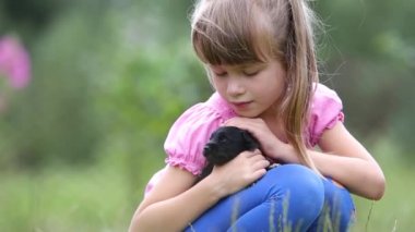 Güzel bir kız çocuğu yazın dışarıda köpek yavrusuyla oynuyor..