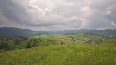 Genç kadın bir yaz günü dağ manzarasının tadını çıkarıyor. Doğa ortamında dinlenme ve meditasyon.
