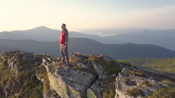 登山者站在岩石山顶上欣赏壮丽的景色 登山者望着山中日出 — 图库视频影像