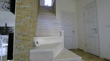 Çatı katının iç kısımlarında modern merdivenler var. Dekoratif kireçtaşı duvarları ve ak meşe merdivenleri olan modern koridor..