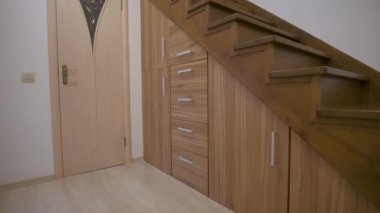 Çok katlı evdeki parlak ahşap merdivenleri olan lüks koridorlu modern mimari. Merdiven altındaki yuvalarda süzülerek süzülen özel çekmeceler. Depo için alan kullanımı.