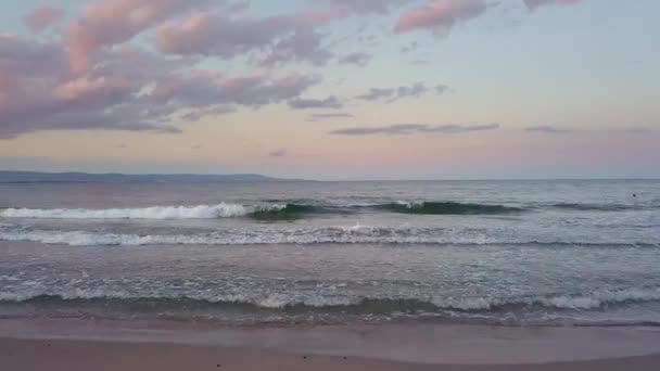 紫色の日没の空の下で青い水の波と海の表面の空中写真 — ストック動画