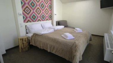 Çatı katında geniş bir otel odasının içinde büyük bir çift kişilik yatağın üzerinde temiz çarşaflar. Modern bir evdeki modern Mansard odası..