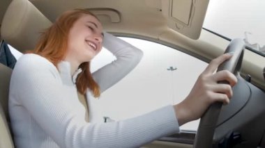 Genç kadın sürücü direksiyonda eğleniyor. Arabada müzik dinliyor..