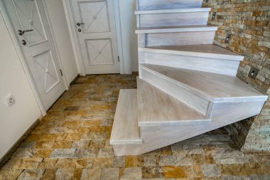 Çatı katının iç kısımlarında modern merdivenler var. Dekoratif kireçtaşı duvarları ve ak meşe merdivenleri olan modern koridor..