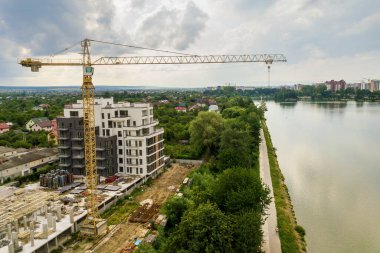 Kule görüntüsü, vinç kaldırma ve inşaat halindeki uzun apartmanın beton iskeleti. Kentsel kalkınma ve gayrimenkul büyüme kavramı.