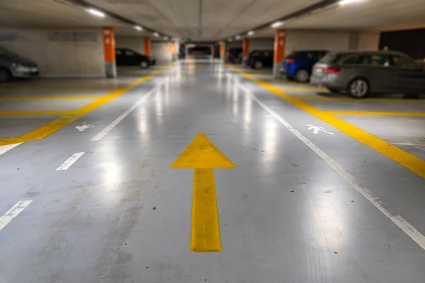 Żółte Oznaczenia Zamazanymi Nowoczesnymi Samochodami Zaparkowanymi Wewnątrz Zamkniętego Podziemnego Parkingu — Zdjęcie stockowe