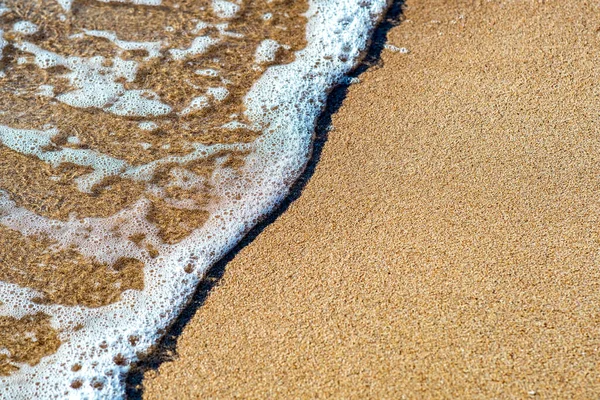 夏の晴れた海岸で黄色の砂のビーチの上に澄んだ青い水と小さな海の波の終わり — ストック写真