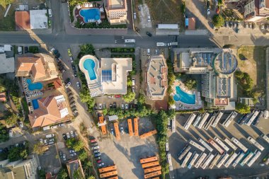 Otellerin çatıları, park etmiş arabaların olduğu sokaklar ve deniz kenarındaki tatil köylerinde mavi suyu olan yüzme havuzları..