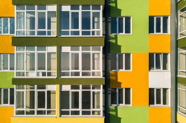 Birçok pencere ve balkonu olan yüksek bir apartman dairesinin havadan görünüşü.