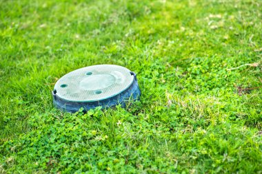 Yeşil çimlerin üzerinde yeşil çim kaplı yeşil plastik boru yakın çekim.
