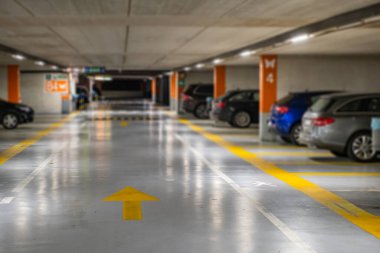 Yellow markings with blurred modern cars parked inside closed underground parking lot. clipart