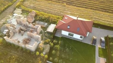 Biri ahşap çatı iskeleti ve diğeri de kırmızı kiremit çatılı iki özel evin yukarıdan aşağıya bakan görüntüsü..