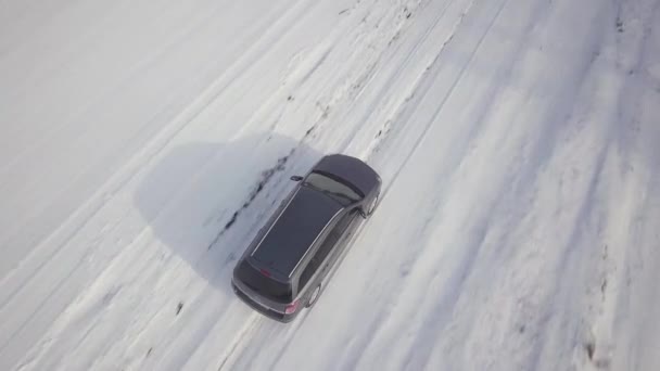 在雪地覆盖的冬季田里 家用轿车在土路上行驶 — 图库视频影像
