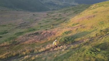 Sırt çantalı bir turist Carpathian dağlarında dağ yolunda koşuyor. Erkek turist kayalık çöl arazisinde koşuyor..