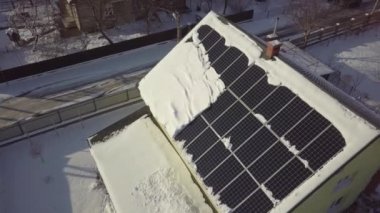 Closeup surface on a house roof covered with solar panels in winter with snow on top.