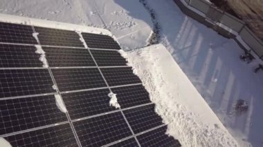 Closeup surface on a house roof covered with solar panels in winter with snow on top.