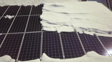 Closeup surface on a house roof covered with solar panels in winter with snow on top.