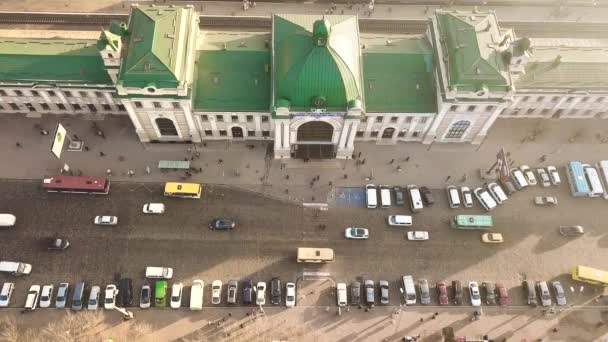多くの車やバスの空中映像は ウクライナのイヴァーノ フランキーフスク市の鉄道駅ビルの前の忙しい街の通りに移動します — ストック動画