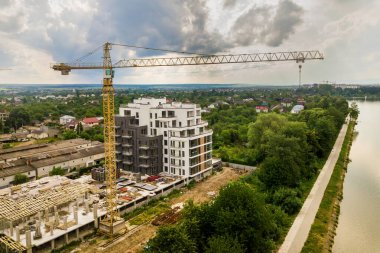 Kule görüntüsü, vinç kaldırma ve inşaat halindeki uzun apartmanın beton iskeleti. Kentsel kalkınma ve gayrimenkul büyüme kavramı.
