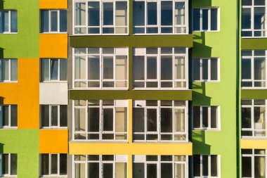 Birçok pencere ve balkonu olan yüksek bir apartman dairesinin havadan görünüşü.