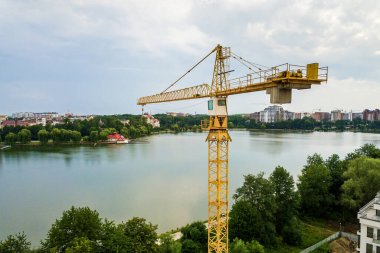 Kule görüntüsü, vinç kaldırma ve inşaat halindeki uzun apartmanın beton iskeleti. Kentsel kalkınma ve gayrimenkul büyüme kavramı.