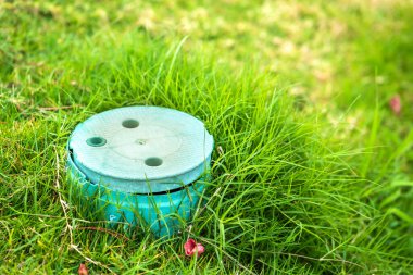 Yeşil çimlerin üzerinde yeşil çim kaplı yeşil plastik boru yakın çekim.