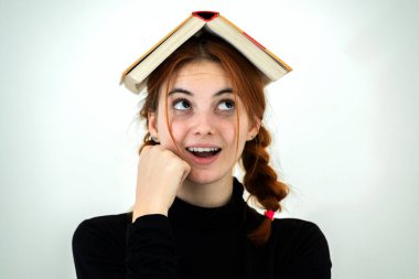 Kafasında açık bir kitapla gülümseyen komik genç kız portresi. Okuma ve eğitim kavramı.