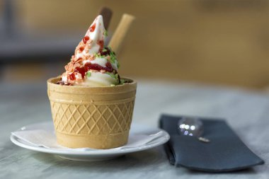 Dondurma Tatlı gofret fincan çikolatalı kurabiye ve yaratıcı dekorasyon Tepesi bulanık renkli iç arka plan üzerinde beyaz plaka.