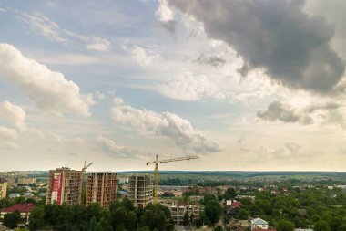 Kule görüntüsü, vinç kaldırma ve inşaat halindeki uzun apartmanların beton iskeleti. Kentsel kalkınma ve gayrimenkul büyüme kavramı.