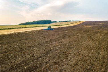 Sonbaharda hasattan sonra siyah tarım tarlasını süren bir traktörün hava görüntüsü.
