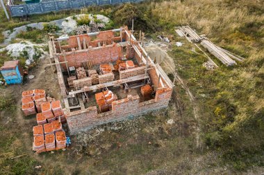 Geleceğin tuğla evi, beton temel zemini ve inşaat için sarı kil tuğla yığınları için hava manzarası.
