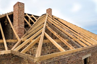 Ahşap çatı iskeleti yapım aşamasında olan özel bir ev. Bitmemiş tuğla bina geliştirme aşamasında.