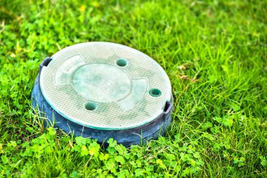 Yeşil çimlerin üzerinde yeşil çim kaplı yeşil plastik boru yakın çekim.