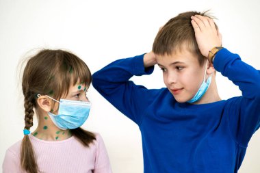 Mavi koruyucu maske takan kız ve erkek çocuk suçiçeği, kızamık ya da kızamık virüsü taşıyorlar. Koronovirüs salgını sırasında çocukların korunması. Covid-19 bulaşıcı hastalık konsepti.