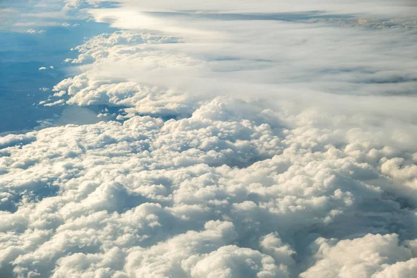 Aerial view of white puffy clouds viewed from an airplane.