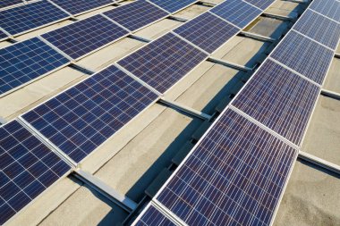 Sanayi binasının çatısına monte edilmiş birçok voltaik güneş panelinin hava görüntüsü.