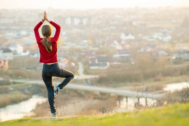 Genç bir kadın şehir manzarasının tadını çıkarıyor. Rahatlama, özgürlük ve sağIık kavramı.
