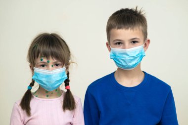 Mavi koruyucu maske takan kız ve erkek çocuk suçiçeği, kızamık ya da kızamık virüsü taşıyorlar. Koronovirüs salgını sırasında çocukların korunması. Covid-19 bulaşıcı hastalık konsepti.