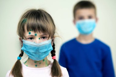 Mavi koruyucu maske takan kız ve erkek çocuk suçiçeği, kızamık ya da kızamık virüsü taşıyorlar. Koronovirüs salgını sırasında çocukların korunması. Covid-19 bulaşıcı hastalık konsepti.