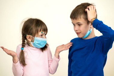 Boy and girl wearing blue protective medical mask ill with chickenpox, measles or rubella virus with rashes on body. Children protection during epidemic of coronovirus. Covid-19 contagion concept. clipart