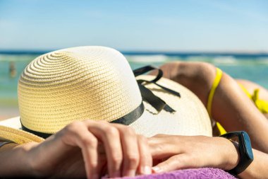 Deniz kıyısında güneş banyosu yaparken plaj sandalyesinde uzanan genç bir kadının kalçasına ve omzuna yakın çekim.