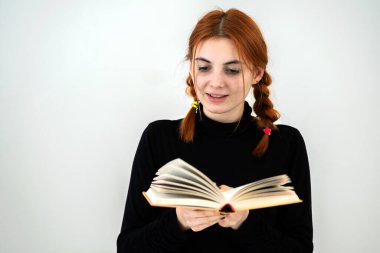 Genç güzel kız elinde açık bir kitap okudu. Okuma ve eğitim kavramı.