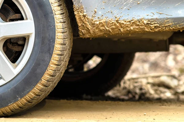 Close up of dirty car wheel with rubber tire covered with yellow mud.