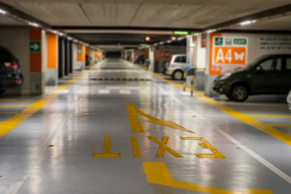 Żółte Oznaczenia Zamazanymi Nowoczesnymi Samochodami Zaparkowanymi Wewnątrz Zamkniętego Podziemnego Parkingu — Zdjęcie stockowe